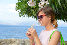 Brunette Girl Holding A White Flower With Seaside In Background