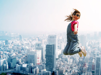 Wall Mural - happy little girl jumping over city background