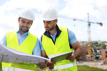 Wall Mural - Engineer and worker watching blueprint on construction site