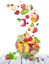 Fruit Salad In Glass Bowl With Ingredients In The Air On White W