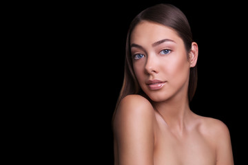 close portrait of a beautiful girl with a natural make-up nude. Isolated on black background. Copy space.