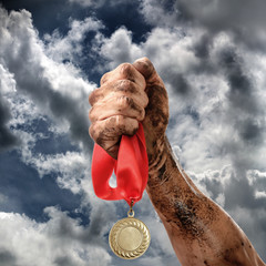 Wall Mural - Golden medal in dirty hand on sky background