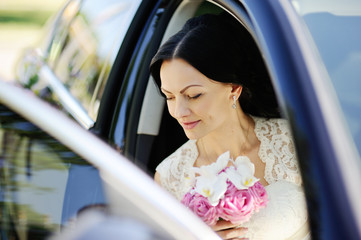 beautiful bride with a wedding bouquet in a dark car