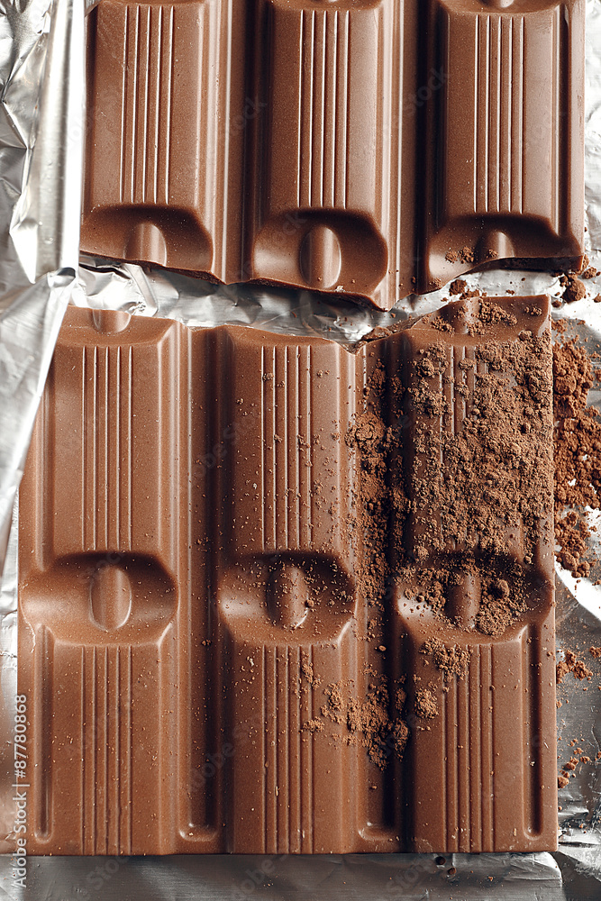 Bar of chocolate with cocoa on foil, closeup