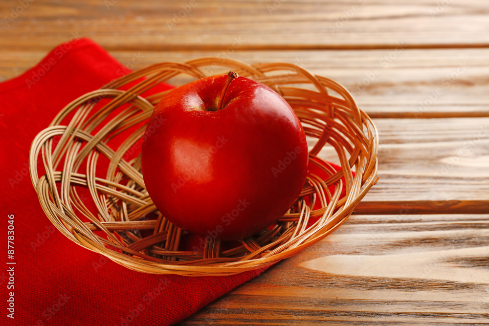 Apple in wicker basket with napkin on wooden background