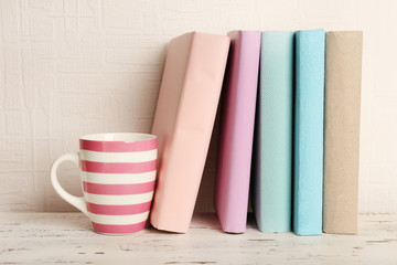 Canvas Print - Books and cup on wooden shelf on wallpaper background