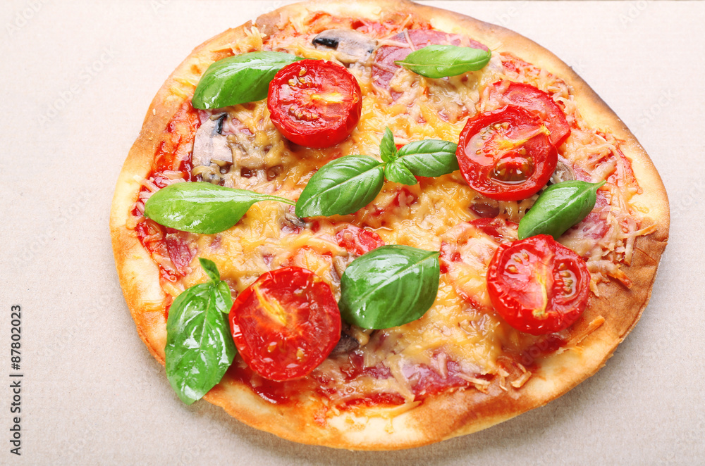 Tasty pizza with vegetables and basil in cardboard box close up