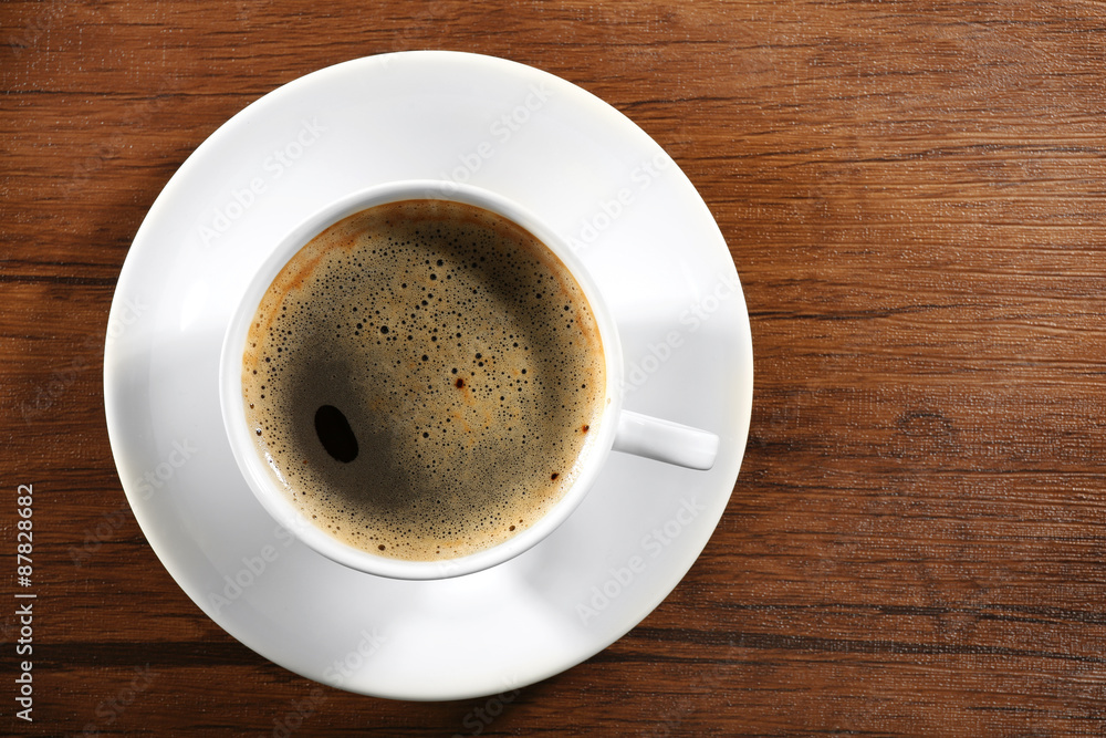 Cup of fresh coffee on wooden table, top view