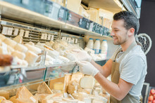 Shop Assistant Restocking Cheese Aisle