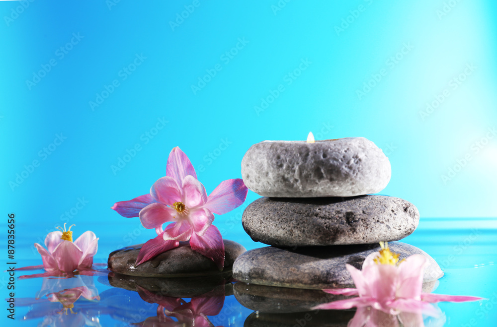Stack of spa stones with flowers on blue background