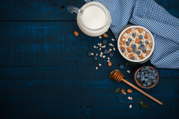 Wall Mural - A healthy breakfast on a dark blue wooden background: Oatmeal, milk, blueberries, honey and almonds. Rustic style.