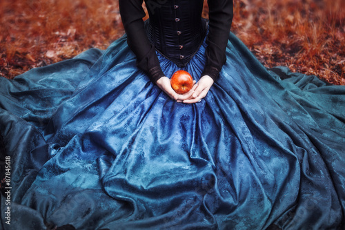 Plakat Królewna Śnieżka ze słynnym czerwonym jabłkiem. Dziewczyna trzyma dojrzałego