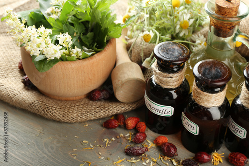 Obraz Dibond Herbs, berries and flowers with mortar, on wooden table background