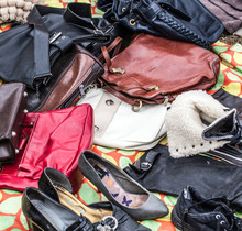 Mix Of Second Hand Leather Women Purses And Bags On Sale At Garage Sale On Grass For Welfare, Recycling Or Selling For Cheap To Cope With Over-consumption And Fashion