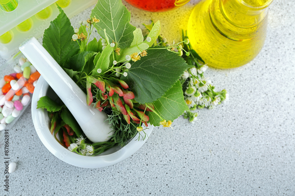 Herbs in mortar, test tubes and pills,  on table, on light background
