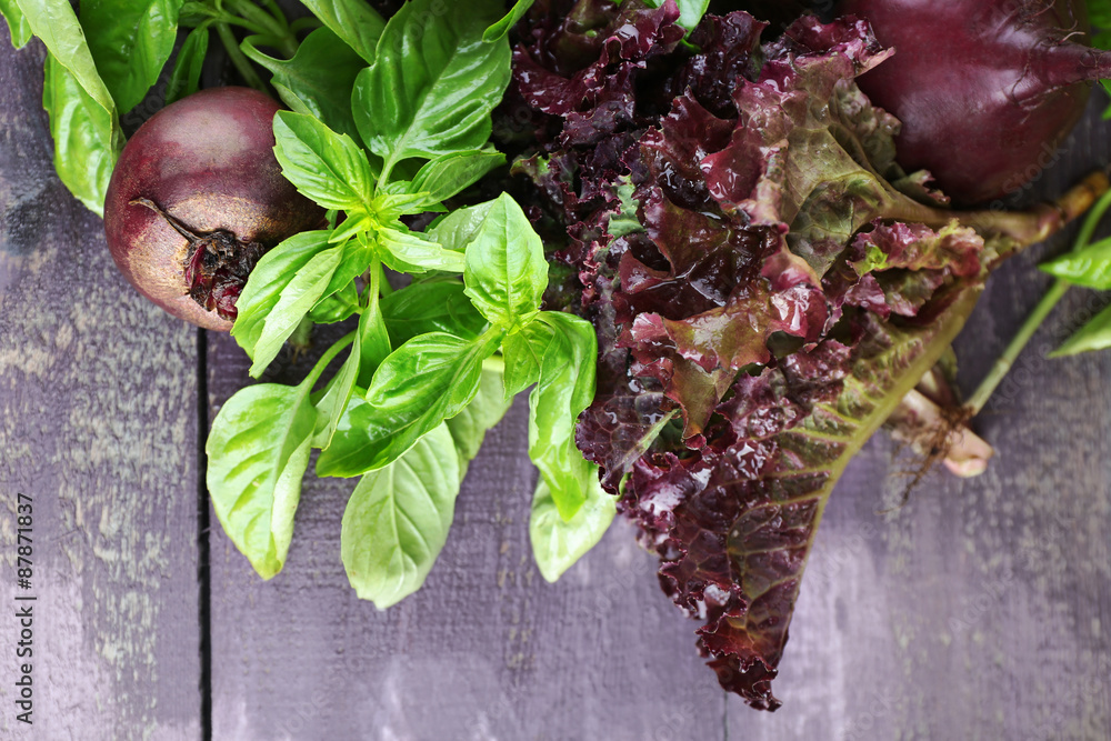 Red beets with greens on wooden table close up