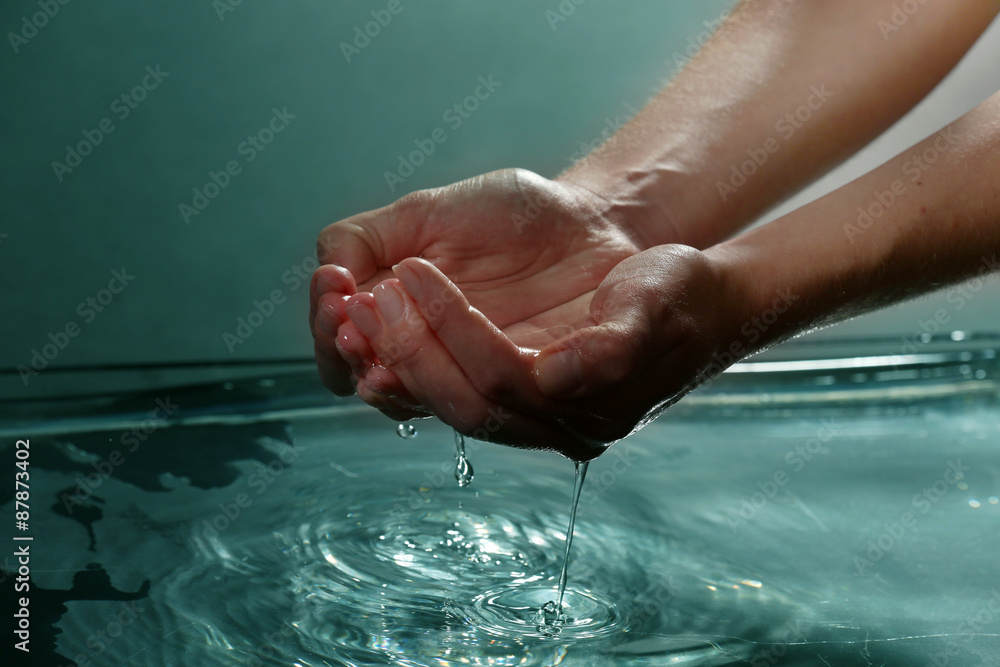 Female hands with water splashing on dark background