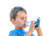 Boy using inhaler for asthma in village with summer sunset