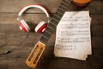 Poster - music recording scene with guitar, music sheets and headphones on wooden table, closeup