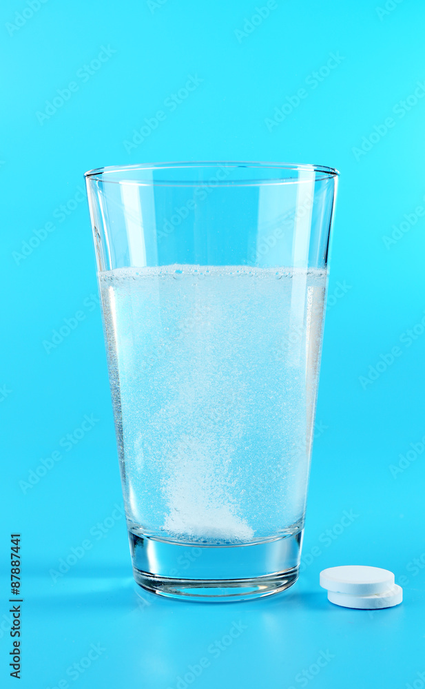 Glass of water and pills on blue background