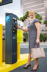 Happy and smile senior aged business woman 55-65 years with a lovely charming smile paying for parking in the street. Positive human emotion, facial expression