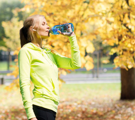 Wall Mural - woman drinking water after doing sports outdoors