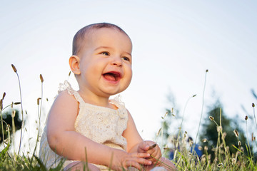 Beautiful baby sitting in the grass on the nature in the park.