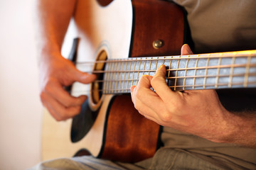 Wall Mural - Young man playing on acoustic guitar close up