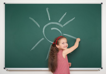 girl drawing sun on school board