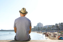 Portrait From Behind Of A Man Sitting Alone Looking At The Beach