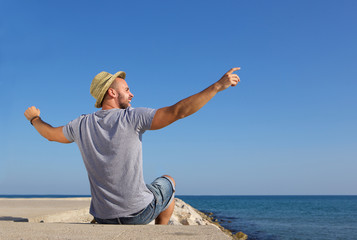 Sticker - Man sitting by the sea with arms spread open