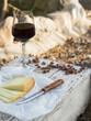 Pieces of cheese and raisins with a red wine glass on a old wood table