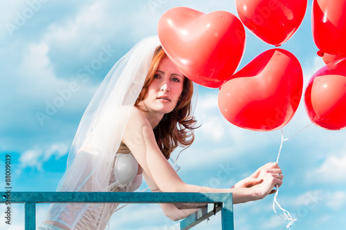 Fotografía Bride with red balloons on balcony in lingerie