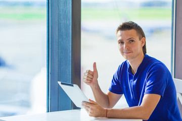 Young businessman working with laptop at airport cafe w