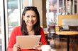 © sittinan - Happy entrepreneur working with a phone and tablet in a coffee shop in the street