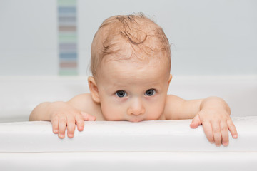adorable baby trying to get out of the bath.