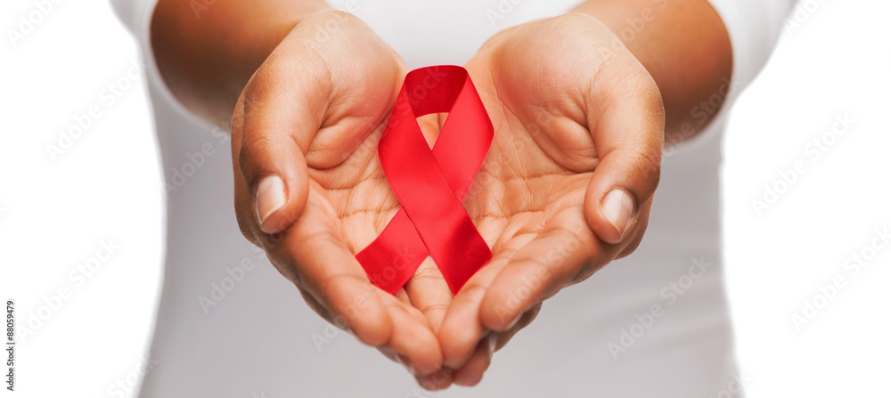 hands holding red AIDS awareness ribbon - obrazy, fototapety, plakaty 