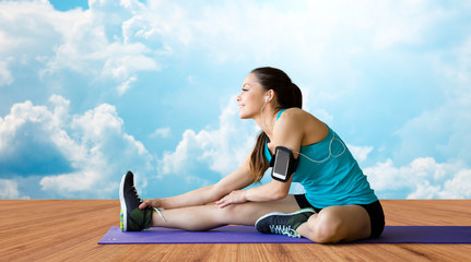 Poster - smiling woman stretching leg on mat over clouds