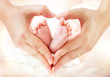 Leinwandbild Motiv baby feet in mother hands - hearth shape
