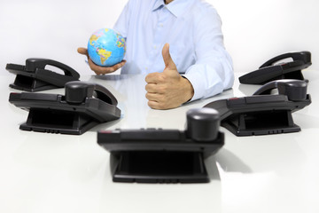 globe and like hand with office phones on desk, global internati