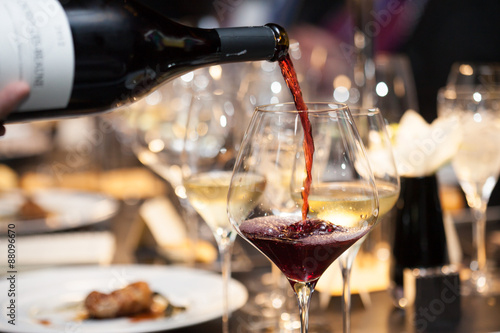 Foto waitress pour red wine in the glass on the table in restaurant