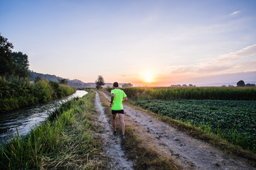 Poster - Ragazzo che corre all'alba su strada di campagna in estate