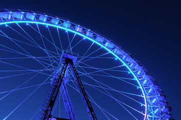 ferris wheel with blue and light blue illumination against night sky