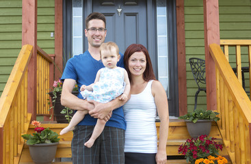 Portrait of couple with their adorable daughter in front of house