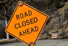 Tilted Orange Road Closed Ahead Sign