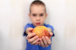 gift to teacher. timid boy holds out an apple to the teacher
