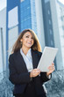 © zadorozhna - Successful businesswoman or entrepreneur using a digital tablet computer, standing in front of his office.