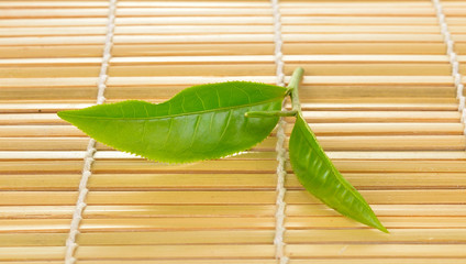 Wall Mural - Fresh green tea leaf on bamboo  background