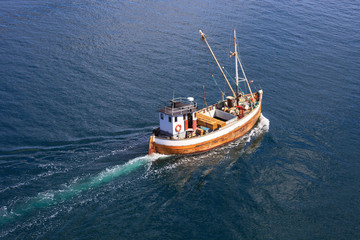 Old wooden fishing boat trawler on sea.