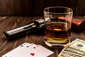 Wall Mural - Glass of whiskey and playing cards with revolver and money on the wooden table